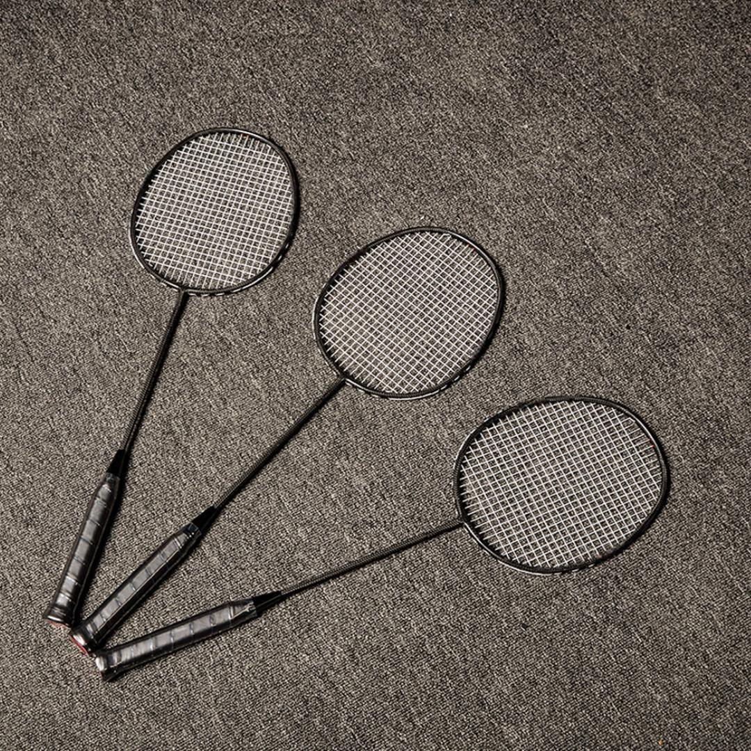 Three carbon fiber badminton rackets with black frames and strings, displayed on a gray textured surface.