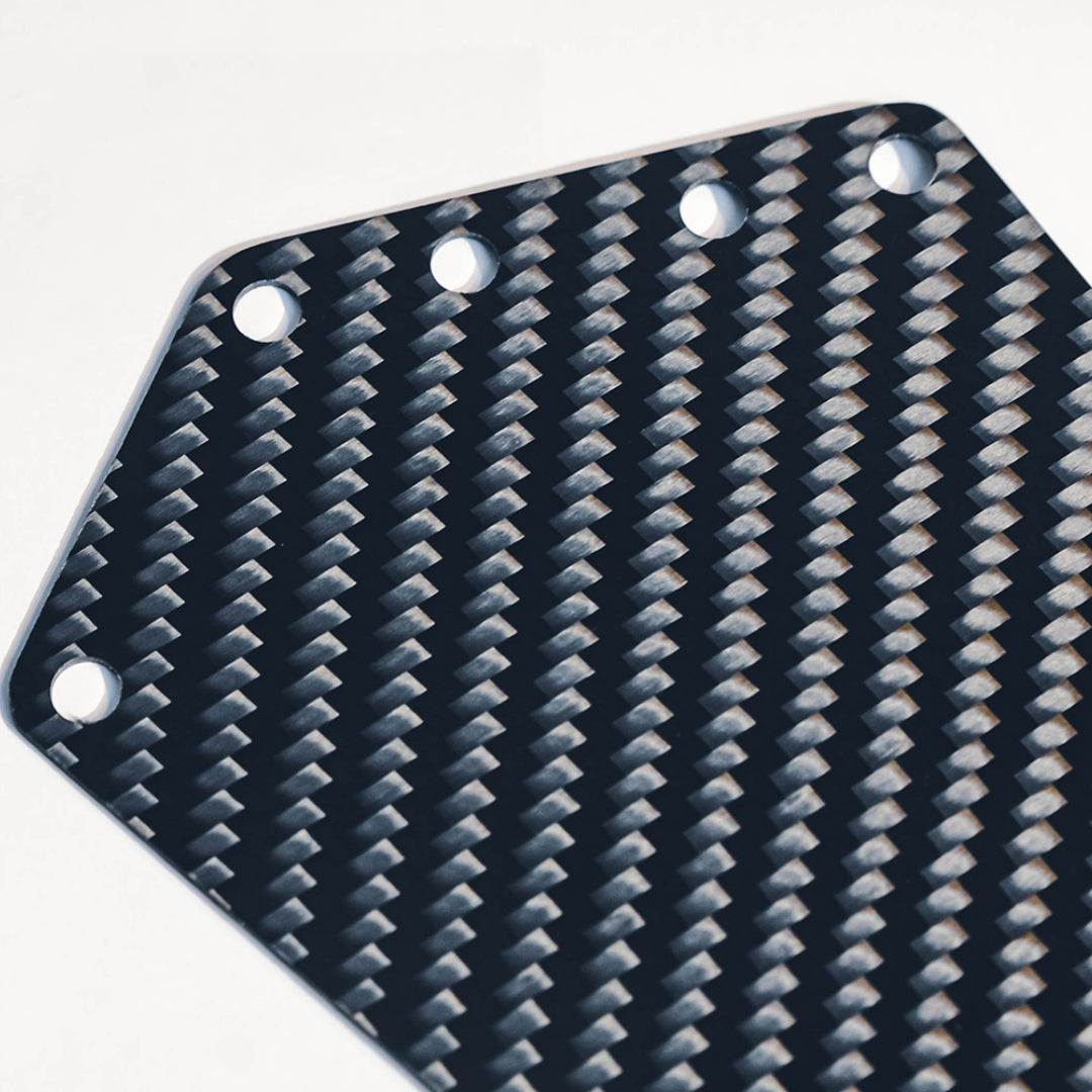 Close-up of a carbon fiber bicycle number plate showcasing its distinct woven pattern and mounting holes.