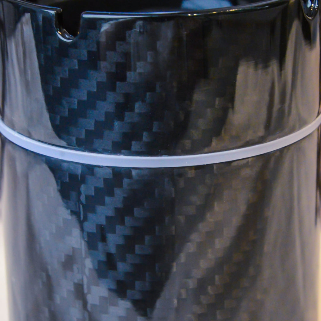 Close-up detail of a 3K carbon fiber car ashtray, highlighting its distinct woven pattern, glossy finish, and white accent ring.