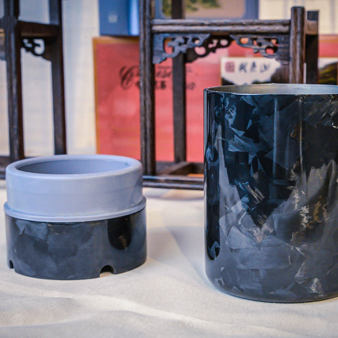 Close-up of forged carbon fiber car ashtrays with a distinct fragmented pattern, displayed against traditional Chinese wooden craftsmanship.