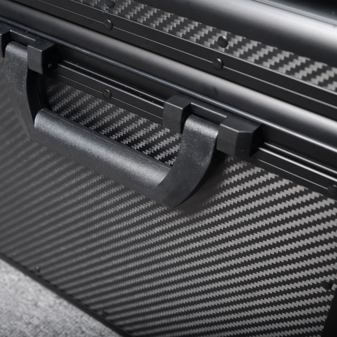 Close-up detail of a 3K carbon fiber car storage trunk, showcasing the black handle and distinctive woven pattern, placed on a gray textured surface.
