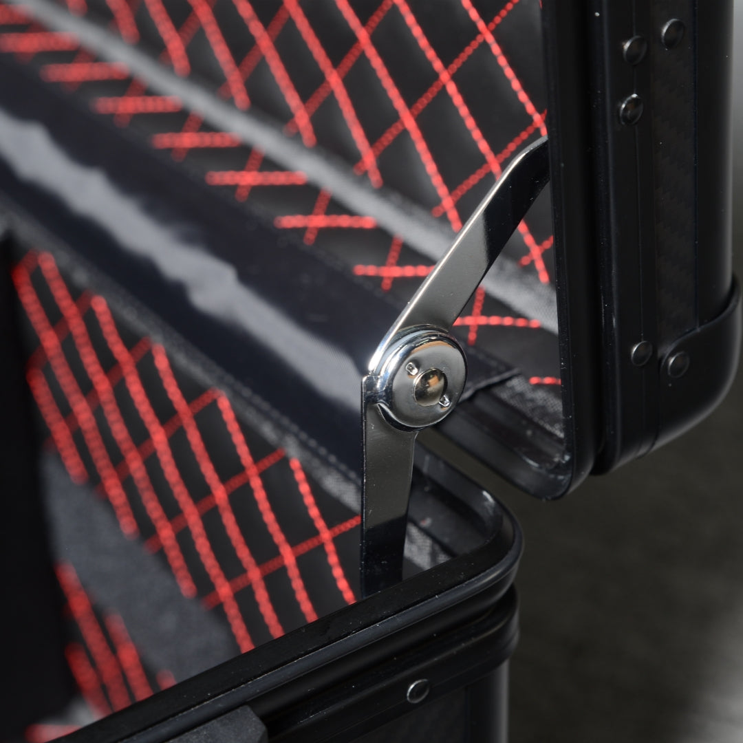Close-up detail of a 3K carbon fiber large car storage trunk, highlighting the metallic hinge and the quilted interior with red stitching.