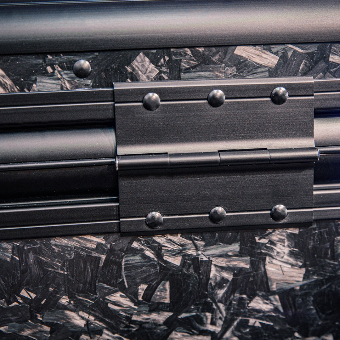 Close-up detail of the back side of a large forged carbon fiber car storage trunk, highlighting the chopped carbon fiber pattern and a metal hinge with rivets.