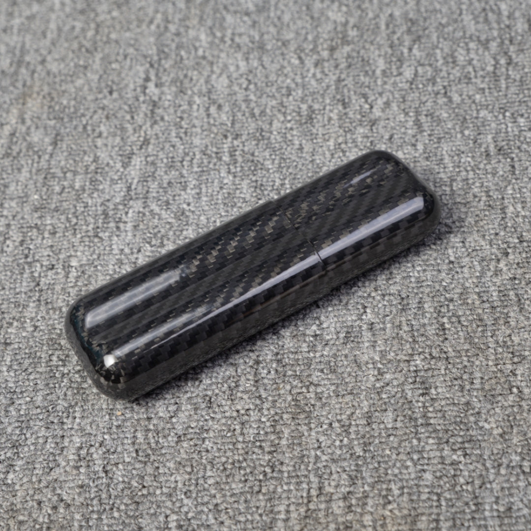 Close-up of a carbon fiber cigar case with a capacity for 2 cigars, featuring a distinct woven pattern, placed on a gray fabric surface.