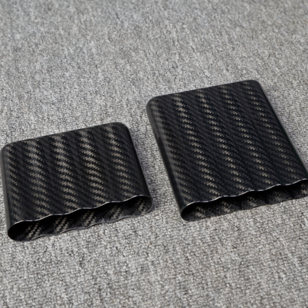Close-up of carbon fiber cigar cases, including one with a capacity for 5 cigars, showcasing a distinct woven pattern, placed on a gray fabric surface.