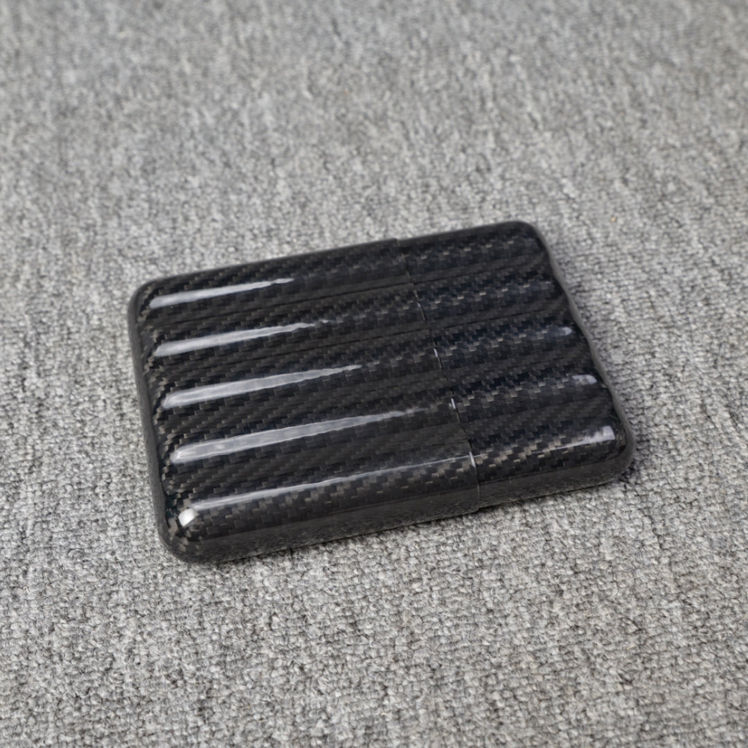 Close-up of a carbon fiber cigar case with a capacity for 5 cigars, featuring a distinct woven pattern, placed on a gray fabric surface.