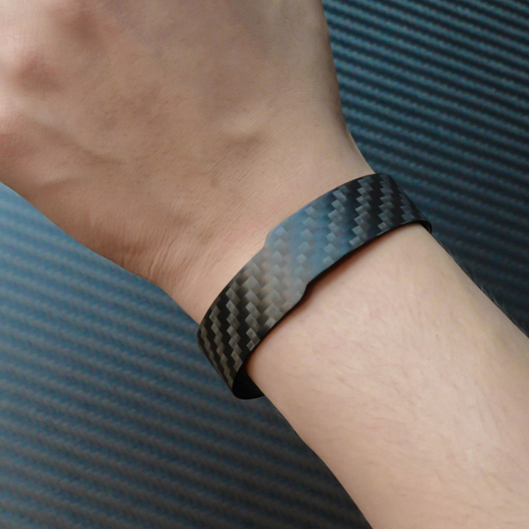 A 3K carbon fiber cuff bracelet with a distinct weave pattern, worn on a wrist, against a carbon fiber textured background.