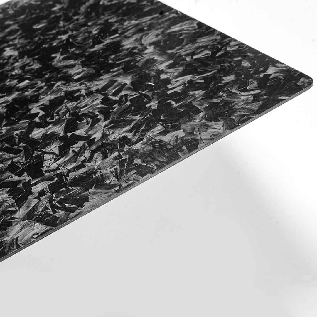 Close-up angled detail of a forged carbon fiber clipboard showcasing its distinct chopped texture and sleek finish against a clean white background.