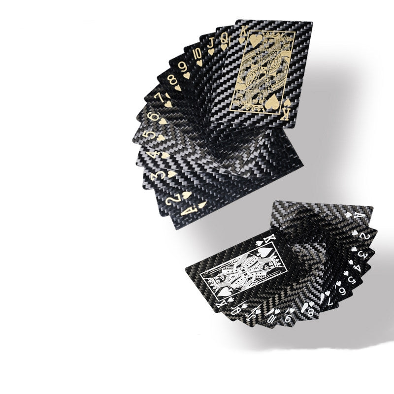 Close-up of carbon fiber playing cards with black and gold/white detailing.