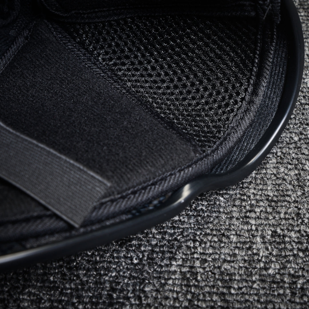 Close-up detail of the interior of a 3K plain weave carbon fiber tactical mask, featuring black padding, mesh fabric, and an adjustable strap, placed on a textured surface.