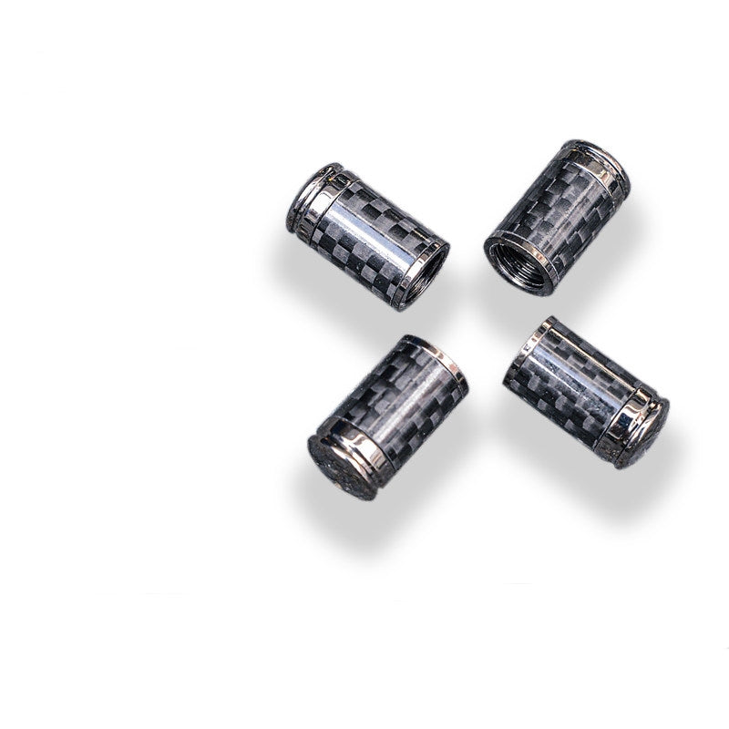 Close-up of four carbon fiber car tire valve stem caps with chrome detailing.