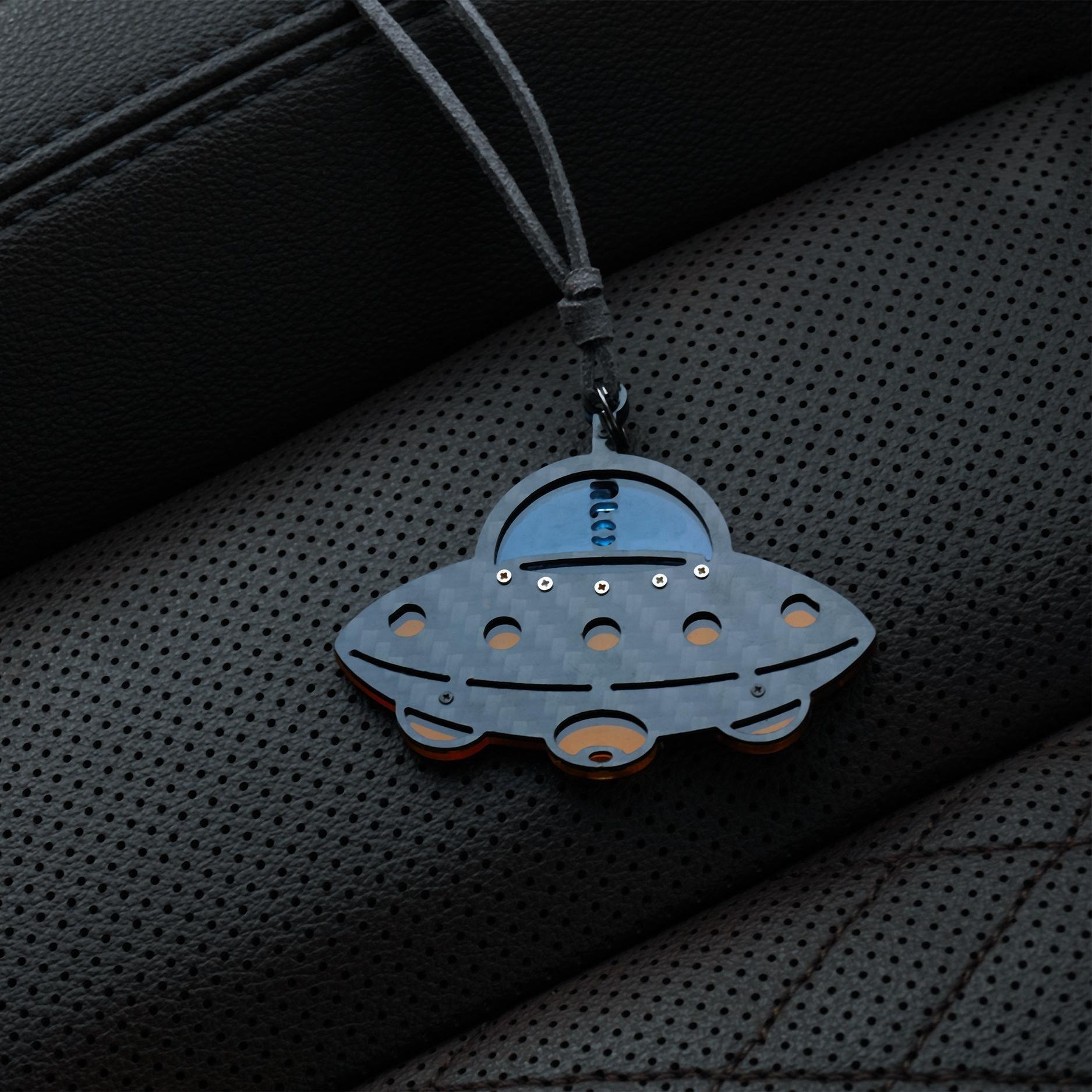 UFO-shaped accessory with a gray carbon fiber-textured body: It features a glossy blue cockpit section