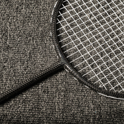 Close-up of a carbon fiber badminton racket showcasing the distinct carbon fiber texture on the frame and shaft, with white strings