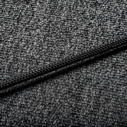 Close-up of a carbon fiber badminton racket shaft showcasing its distinct textured pattern, laid on a gray textured surface.
