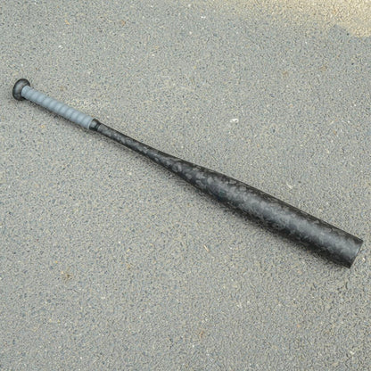 Forged carbon fiber baseball bat with a distinct chopped carbon fiber pattern and gray grip, laid on an asphalt surface.