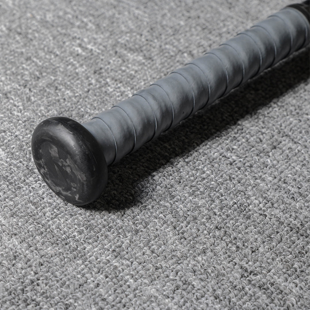 Close-up of the handle and end cap of a forged carbon fiber baseball bat, featuring a gray textured grip and a black end cap with subtle patterns, placed on a gray textured fabric surface.