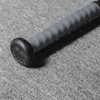 Close-up of the handle and end cap of a forged carbon fiber baseball bat, featuring a gray textured grip and a black end cap with subtle patterns