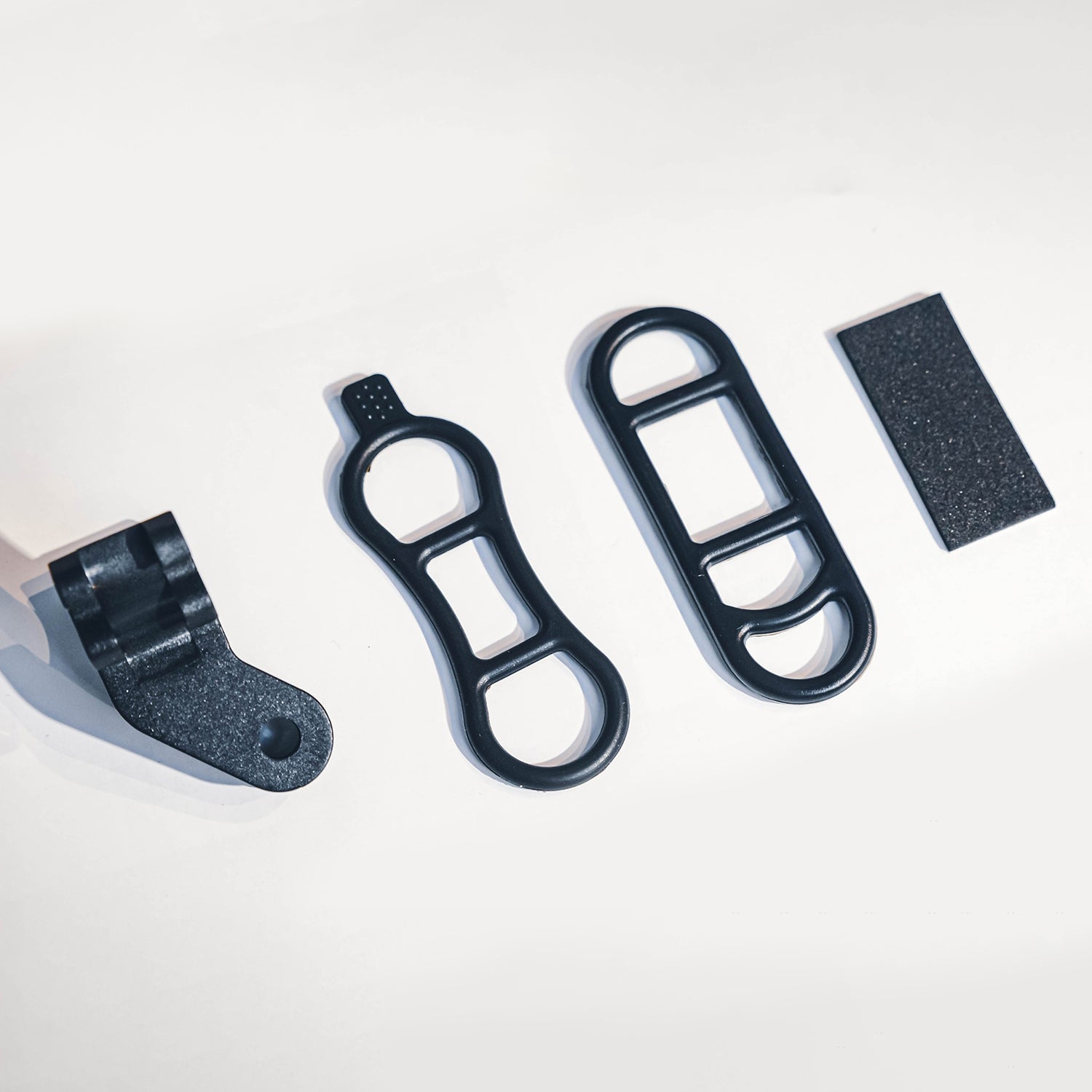 Close-up detail of a black mounting bracket with a metal bolt for a carbon fiber bicycle number plate.