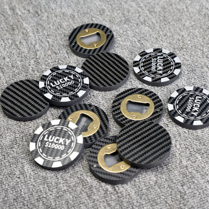 Close-up of multiple carbon fiber bottle openers with a poker chip design, featuring "LUCKY $10000" text and brass bottle opener mechanisms, scattered on a gray textured surface.