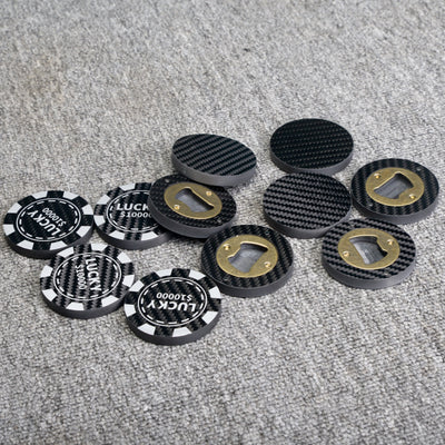 Close-up of multiple carbon fiber bottle openers, scattered on a gray textured surface