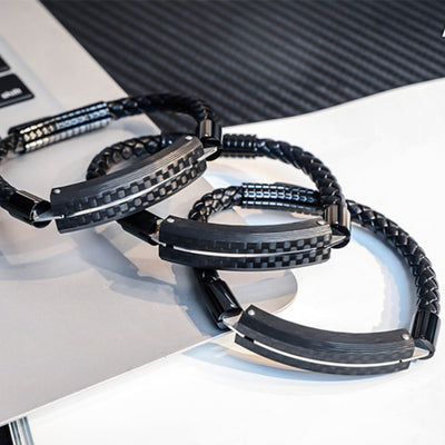 Close-up detail of several carbon fiber bracelets featuring black braided straps and metallic accents