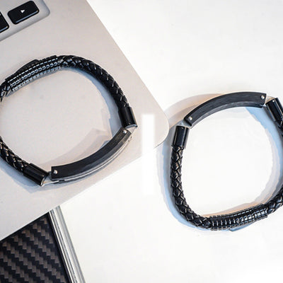 Close-up detail of two carbon fiber bracelets with black braided straps and textured carbon fiber accents