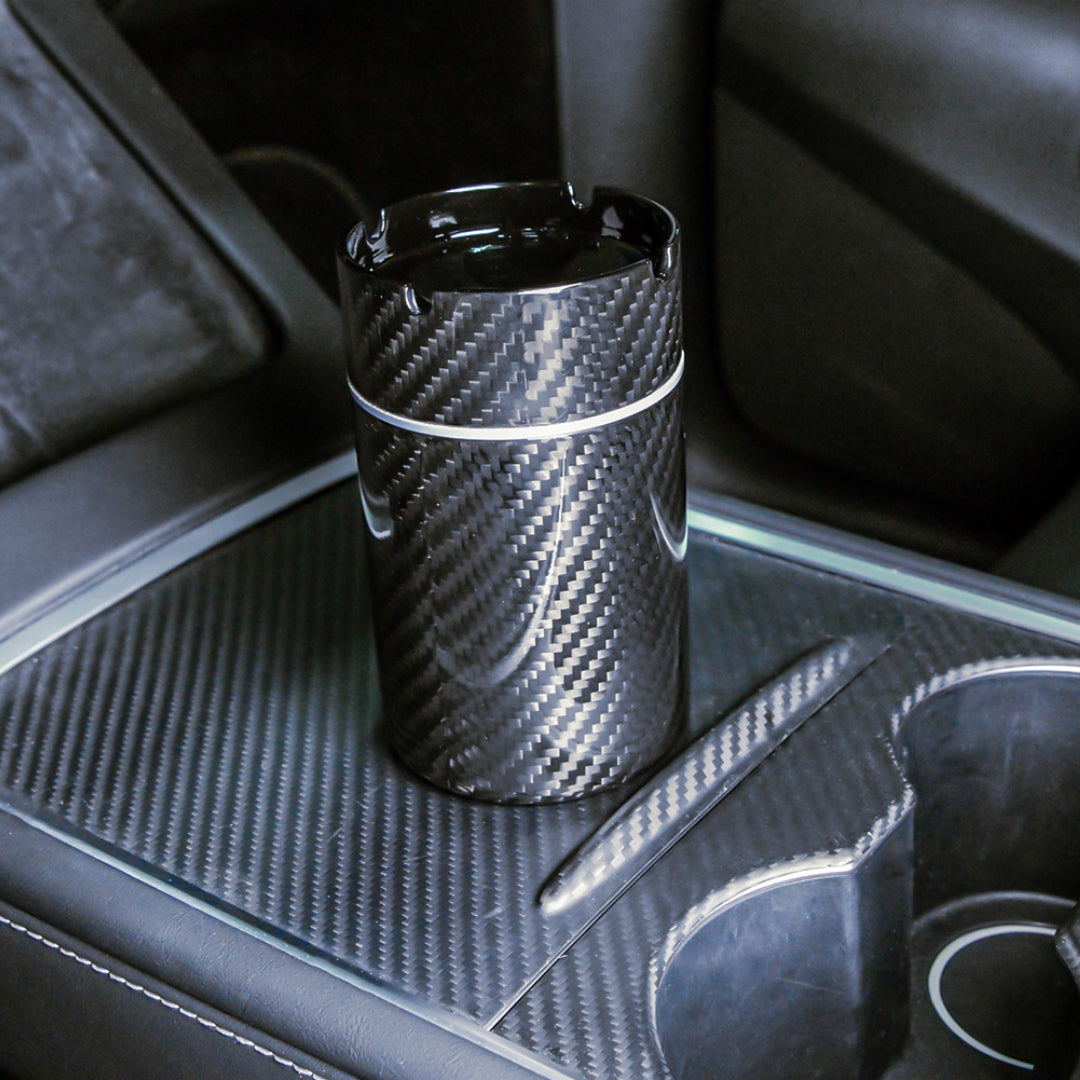 Close-up of a 3K carbon fiber car ashtray with a distinct woven pattern, placed on a carbon fiber-trimmed center console in a vehicle.
