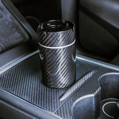 Close-up of a 3K carbon fiber car ashtray with a distinct woven pattern, placed on a carbon fiber-trimmed center console in a vehicle.