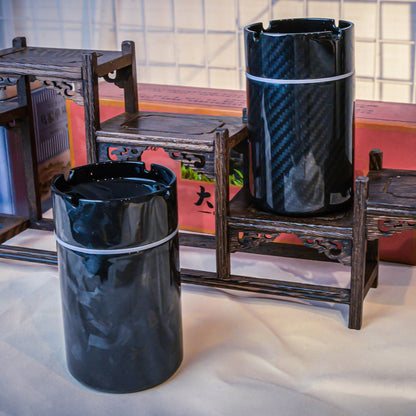 Close-up of two car ashtrays—one with a 3K carbon fiber pattern, the other with a forged carbon fiber pattern—displayed with traditional Chinese wooden decor in the background.