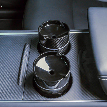 Close-up of two car ashtrays—one with a 3K carbon fiber pattern, the other with a forged carbon fiber pattern—placed in the cup holders of a car's carbon fiber-trimmed center console.
