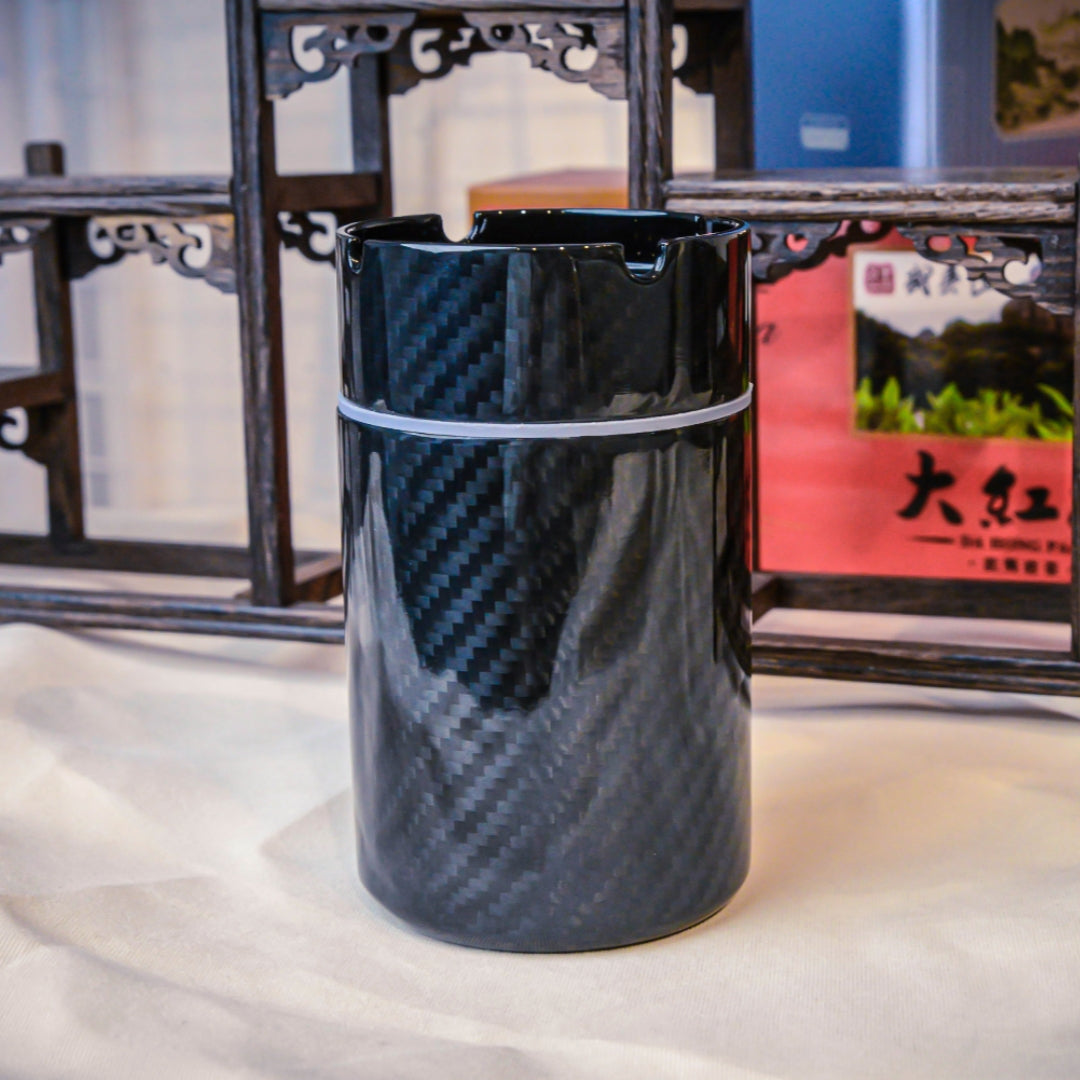 Close-up of a 3K carbon fiber car ashtray with a distinct woven pattern, displayed against traditional Chinese wooden decor.