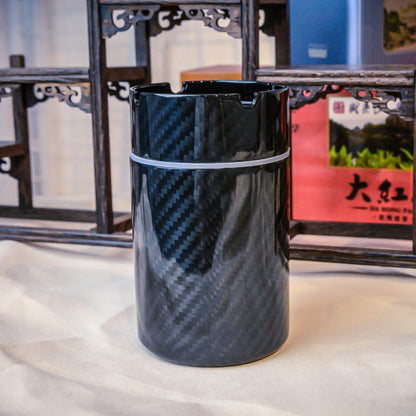 Close-up of a 3K carbon fiber car ashtray with a distinct woven pattern, displayed against traditional Chinese wooden decor.