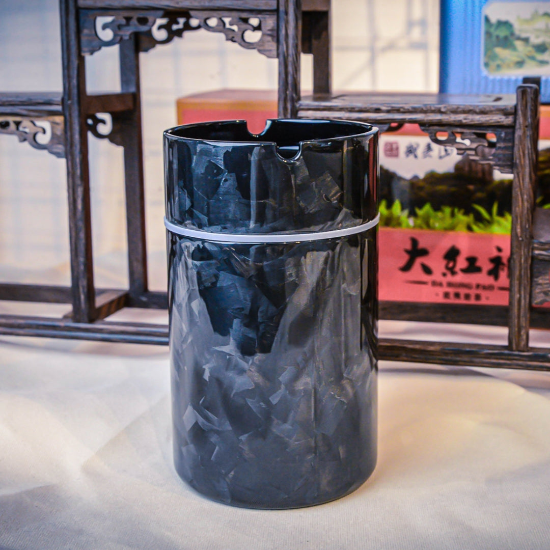Close-up of a forged carbon fiber car ashtray with a distinct fragmented pattern and glossy finish, displayed against traditional Chinese wooden craftsmanship.
