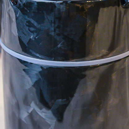 Close-up detail of a forged carbon fiber car ashtray, showcasing its distinct fragmented pattern, glossy finish, and white accent ring.