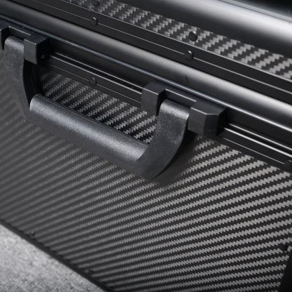 Close-up detail of a 3K carbon fiber car storage trunk, showcasing the black handle and distinctive woven pattern, placed on a gray textured surface.