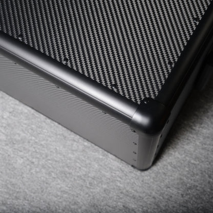 Close-up detail of a 3K carbon fiber car storage trunk, highlighting the woven pattern and metal corner, placed on a gray textured surface.