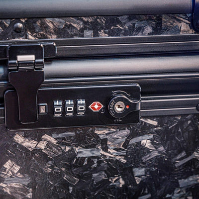 Close-up detail of the combination lock with TSA logo on the bottom part of a large forged carbon fiber car storage trunk