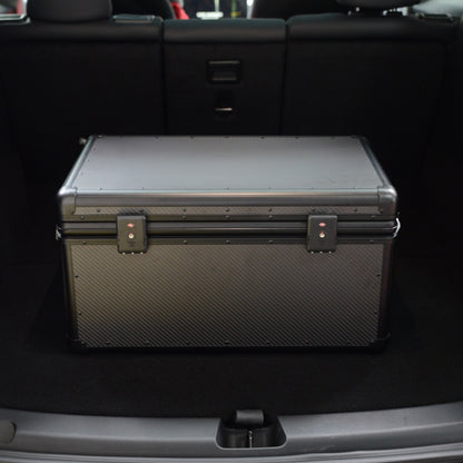 Close-up of a closed large 3K carbon fiber car storage trunk with metallic locks, placed in a car trunk.