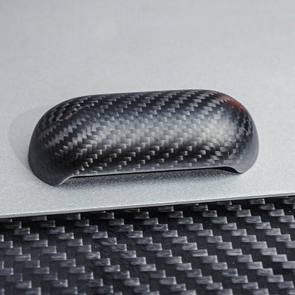 Close-up of the top cover of a 3K carbon fiber AirPods case showcasing the distinct weave pattern, placed on a metallic surface with a carbon fiber textured background.