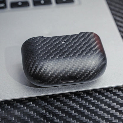 Close-up of the lower part of a 3K carbon fiber AirPods case showcasing the distinct weave pattern, placed on a metallic surface with a carbon fiber textured background.