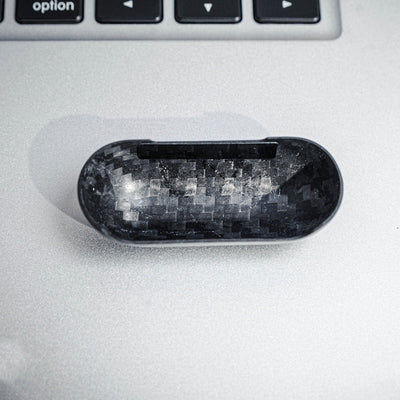 Close-up of the interior of the top half of a carbon fiber AirPods case, showcasing the distinct weave pattern