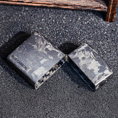 Close-up of an open forged carbon fiber Zippo lighter case with "BUB CARBON" branding, showcasing the unique marbled texture