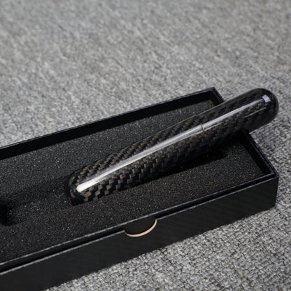Close-up of a carbon fiber cigar tube (single cigar capacity) with a distinct weave pattern, placed in a black box with foam lining on a gray fabric surface.