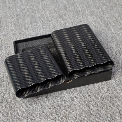 Close-up of carbon fiber cigar tubes with a capacity for 4 cigars, featuring a distinct woven pattern, placed in a black box on a gray fabric surface.