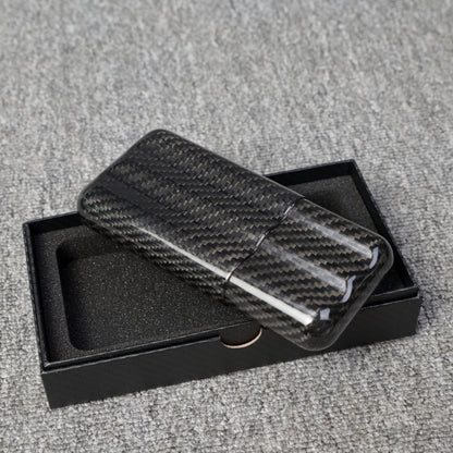 Close-up of a carbon fiber cigar tube with a capacity for 3 cigars, featuring a distinct woven pattern, placed on an open black box with foam lining over a gray fabric surface.