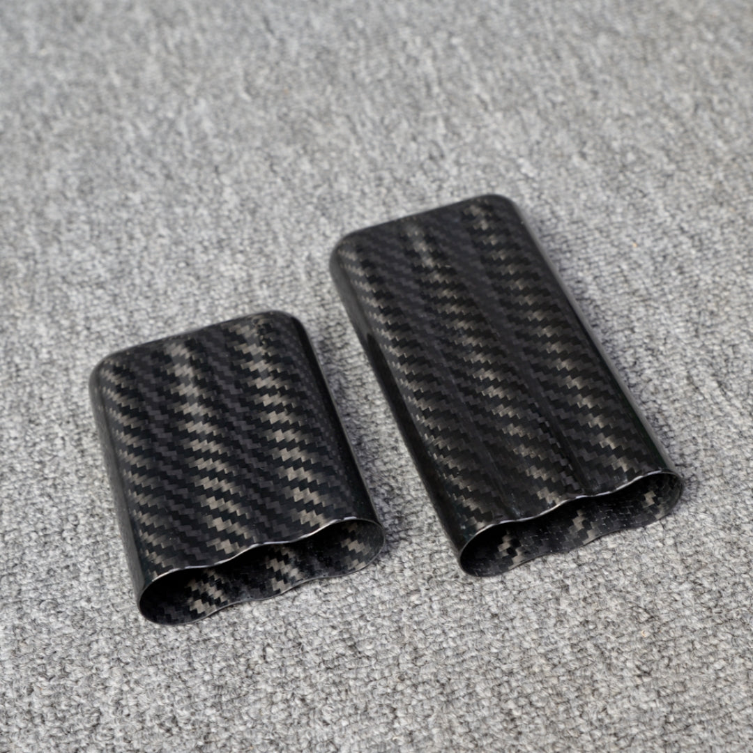 Close-up of carbon fiber cigar tubes with a capacity for 3 cigars, showcasing a distinct woven pattern, placed on a gray fabric surface.