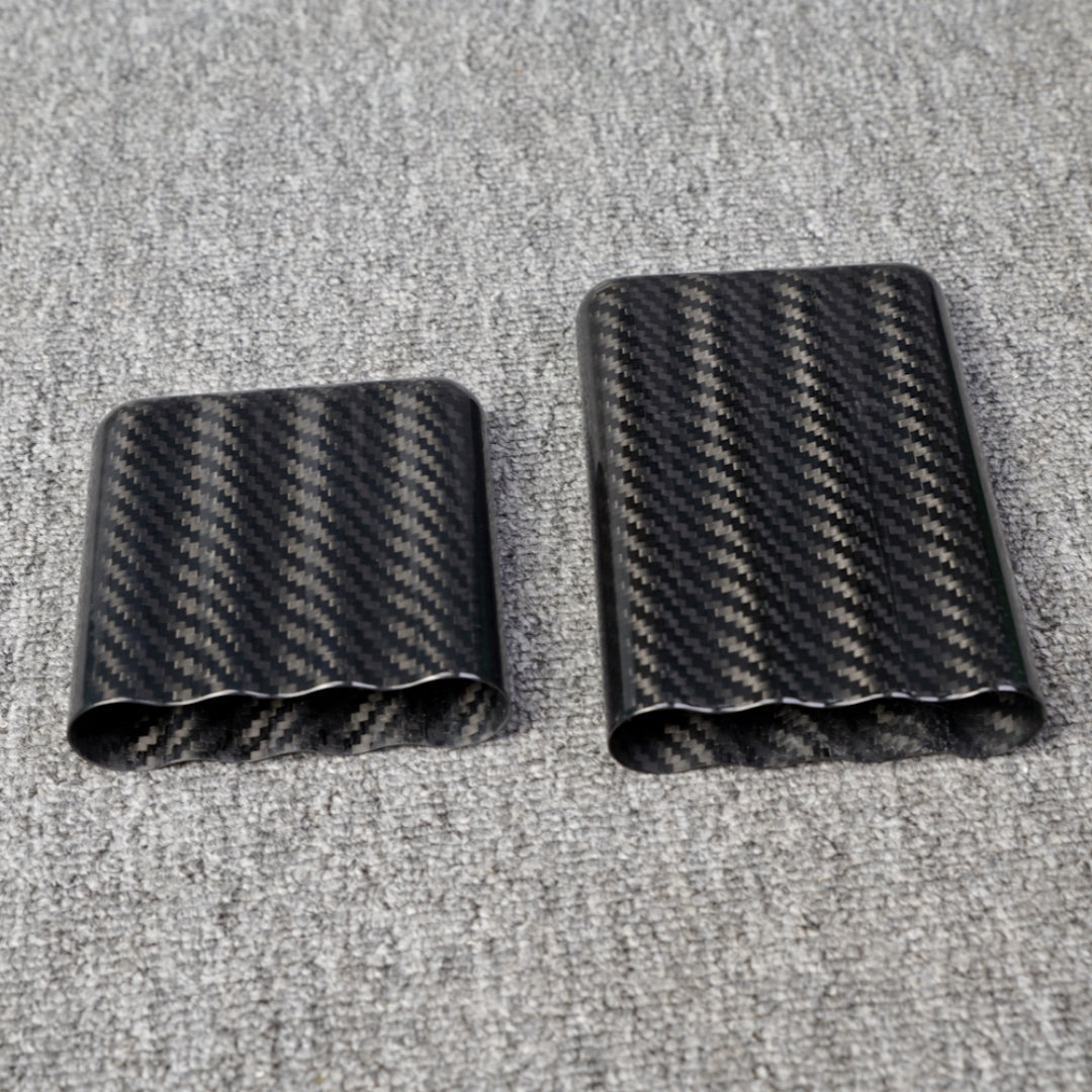 Close-up of carbon fiber cigar cases, including one with a capacity for 4 cigars, featuring a distinct woven pattern, placed on a gray fabric surface.