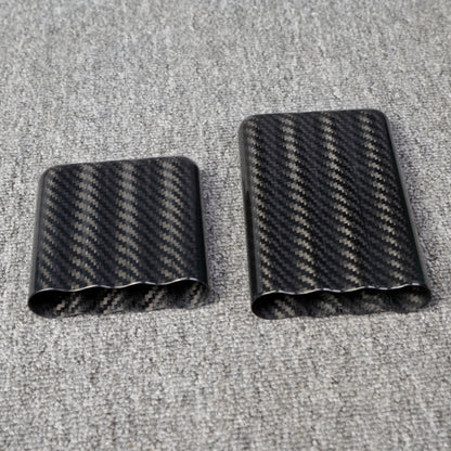Close-up of carbon fiber cigar cases, including one with a capacity for 4 cigars, featuring a distinct woven pattern, placed on a gray fabric surface.