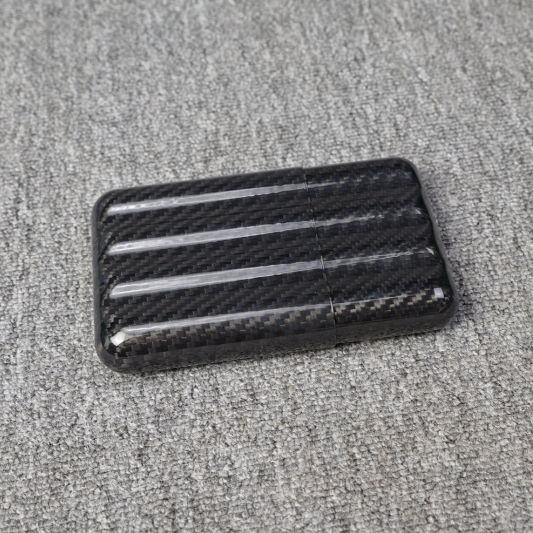 Close-up of a carbon fiber cigar case with a capacity for 4 cigars, featuring a distinct woven pattern, placed on a gray fabric surface.