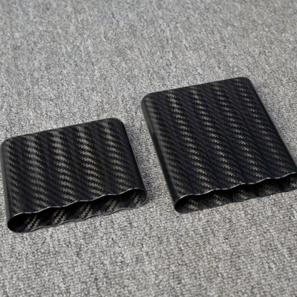 Close-up of carbon fiber cigar cases, including one with a capacity for 5 cigars, showcasing a distinct woven pattern, placed on a gray fabric surface.